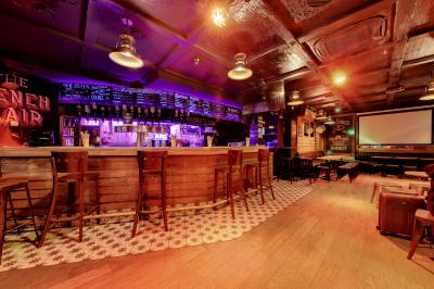 Salle de bar avec des murs en bois, des tables et chaises alignées, et une grande inscription ’French Flair’ sur le mur.
