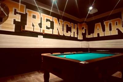 Salle intérieure d’un bar avec des murs décorés du texte ’French Flair’, des tables et des chaises en bois.