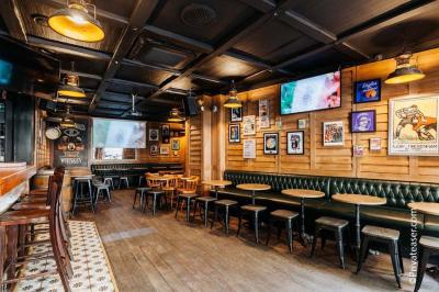 Salle intérieure d’un bar avec des murs décorés du texte ’French Flair’, des tables et des chaises en bois.