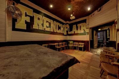 Salle intérieure d’un bar avec des murs décorés du texte ’French Flair’, des tables et des chaises en bois.