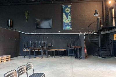 Salle aménagée avec des tables alignées portant des brochures, des bandanas colorés et des bougies, écran et affiches en…