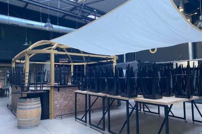 Salle aménagée avec des tables alignées portant des brochures, des bandanas colorés et des bougies, écran et affiches en…