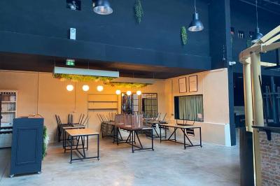 Salle aménagée avec des tables alignées portant des brochures, des bandanas colorés et des bougies, écran et affiches en…