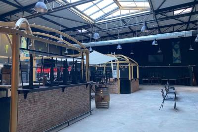 Salle aménagée avec des tables alignées portant des brochures, des bandanas colorés et des bougies, écran et affiches en…