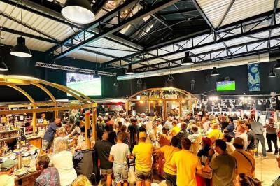 Salle aménagée avec des tables alignées portant des brochures, des bandanas colorés et des bougies, écran et affiches en…