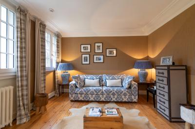 Salon chaleureux avec canapé à motifs bleus, lampes assorties, murs texturés et parquet en bois clair.