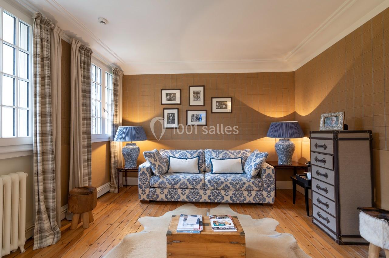 Salon chaleureux avec canapé à motifs bleus, lampes assorties, murs texturés et parquet en bois clair.