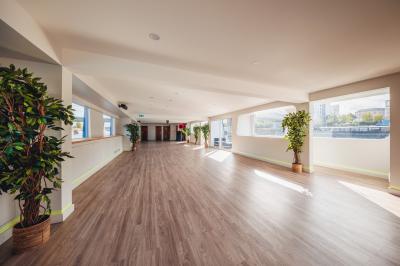 Bateau naviguant sur une rivière avec des passagers debout sur le pont supérieur près d'un quai en pierre.