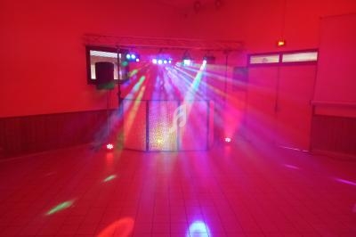 Jeu de lumières colorées projetées dans une salle vide avec une installation de sono et éclairage.