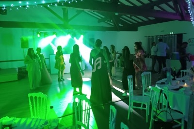 Des personnes dansent sous des lumières vertes dans une salle décorée avec des guirlandes lumineuses.