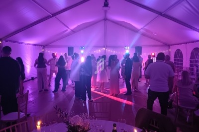 Groupe de personnes dansant sous une tente éclairée par des lumières colorées lors d'un événement festif.