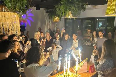 Terrasse d'un restaurant avec des tables dressées, située devant un immeuble moderne et un parking ensoleillé.
