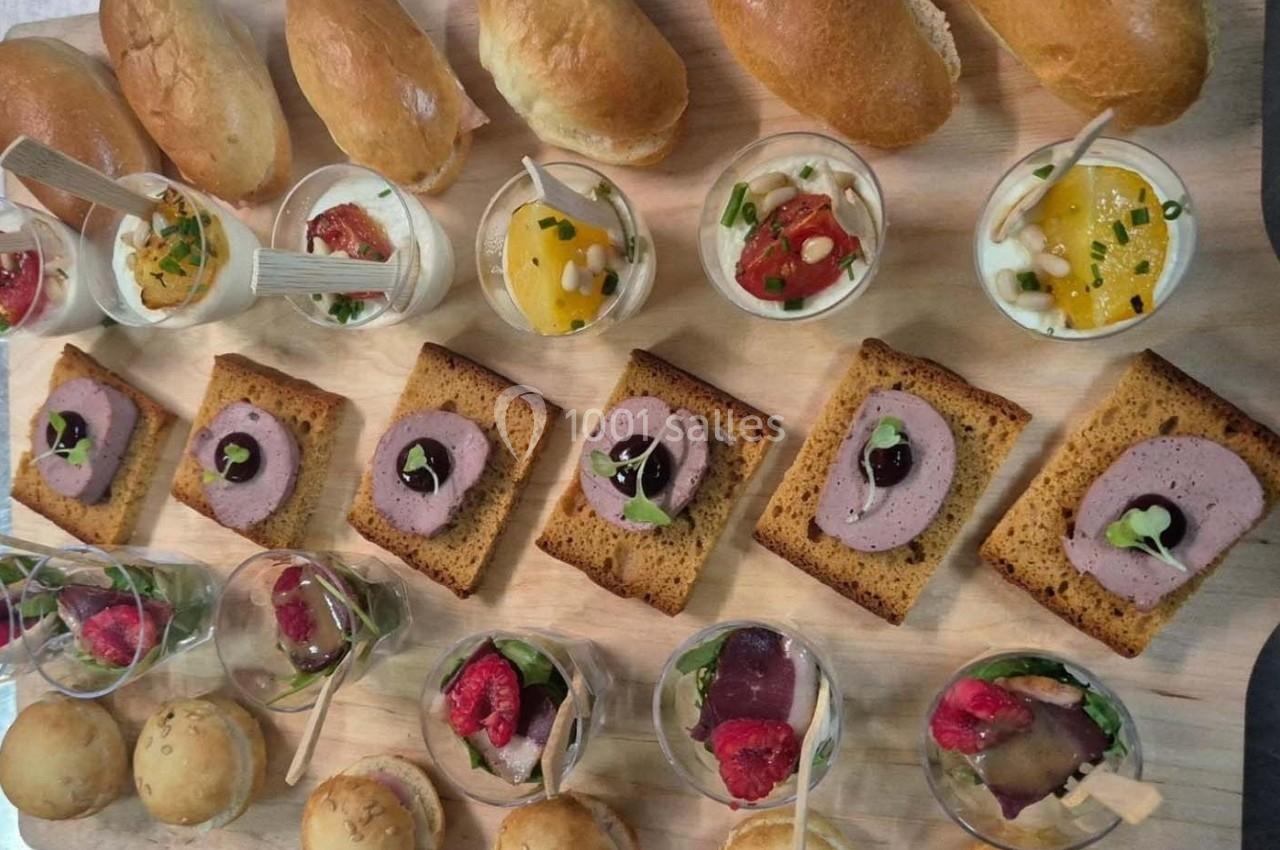 Assortiment de verrines, toasts et pains variés disposés sur une planche en bois.