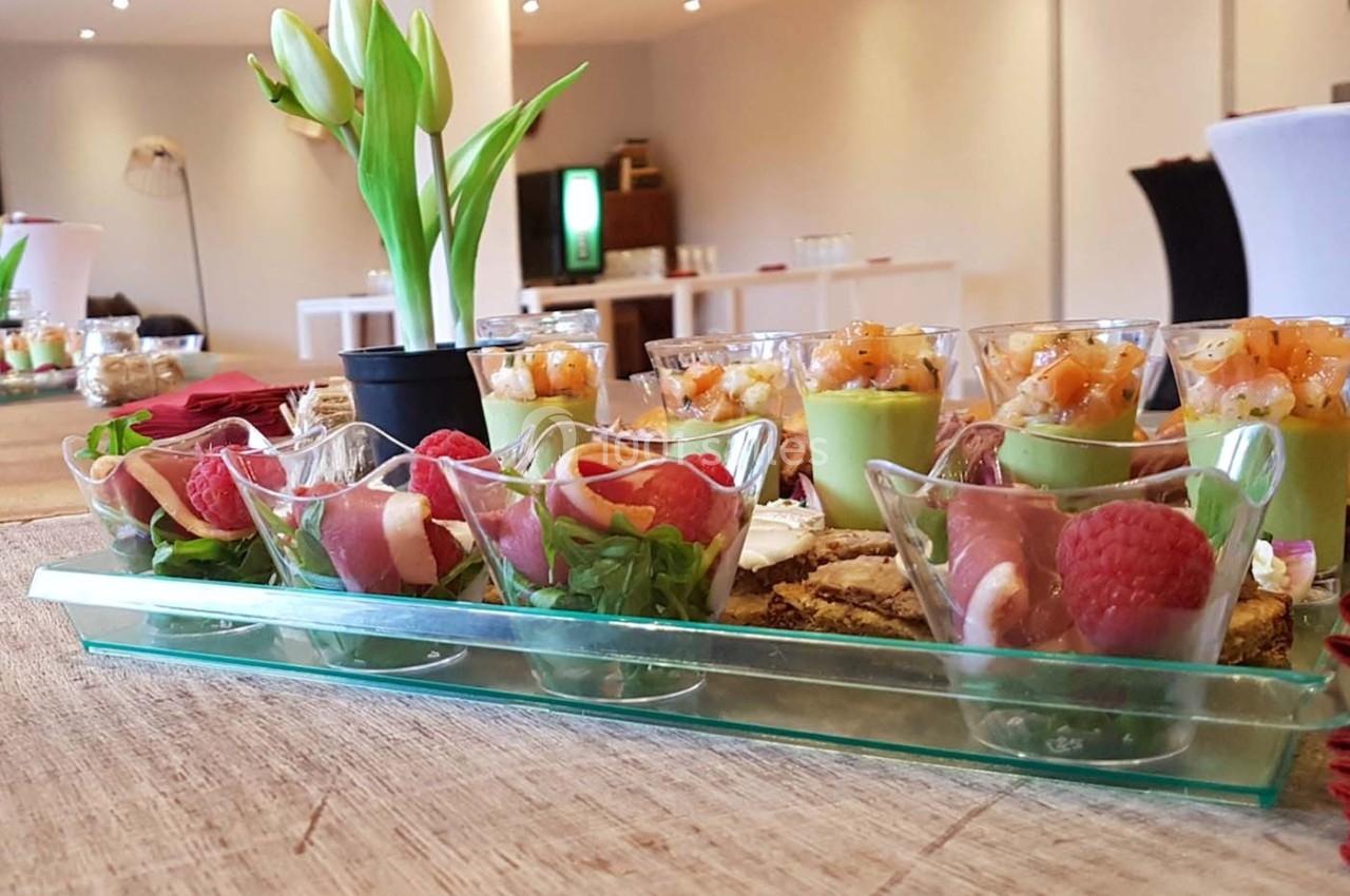 Plateau de verrines colorées avec des ingrédients frais, disposé sur une table en bois dans une salle lumineuse.