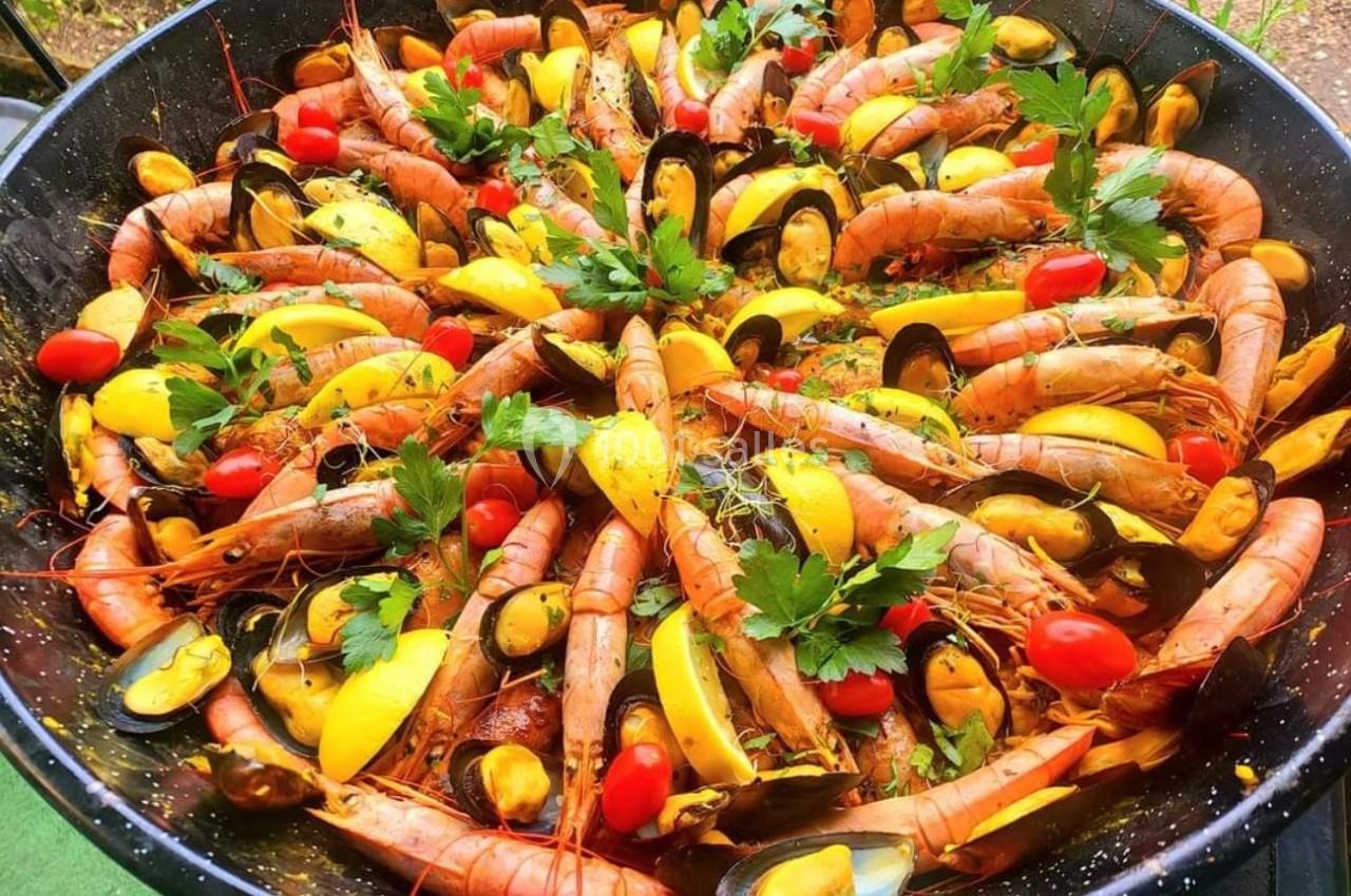 Plat de fruits de mer avec crevettes, moules, tomates cerises, citron et persil dans une grande poêle.