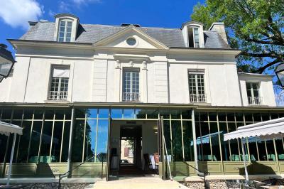 Chambre lumineuse avec lit double, bureau près de la fenêtre, cheminée décorative et télévision murale.