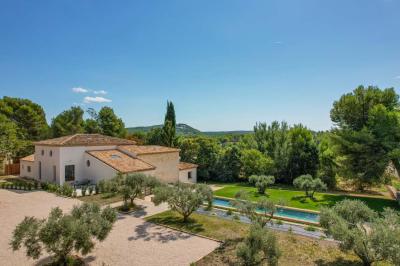 Salon avec canapé beige, fauteuils, table basse, télévision, cheminée en pierre et plafond avec poutres apparentes.
