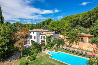 Salon avec canapé beige, fauteuils, table basse, télévision, cheminée en pierre et plafond avec poutres apparentes.