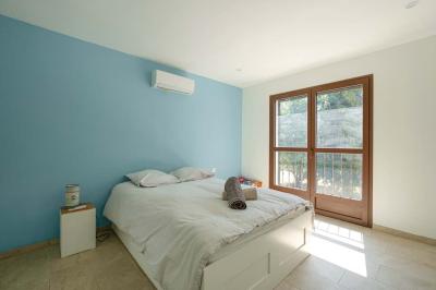 Salon avec canapé beige, fauteuils, table basse, télévision, cheminée en pierre et plafond avec poutres apparentes.