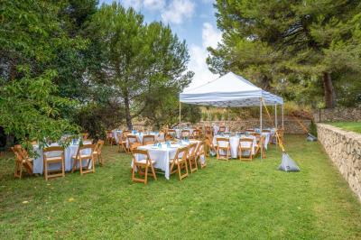 Salon avec canapé beige, fauteuils, table basse, télévision, cheminée en pierre et plafond avec poutres apparentes.