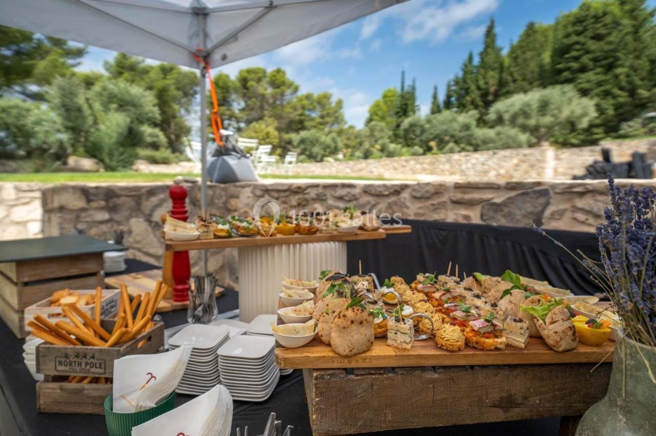 Buffet en plein air avec divers plats et amuse-bouches disposés sur des plateaux en bois, entouré de verdure.