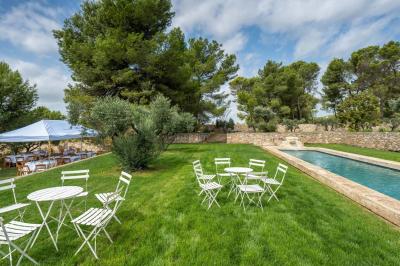 Salon avec canapé beige, fauteuils, table basse, télévision, cheminée en pierre et plafond avec poutres apparentes.