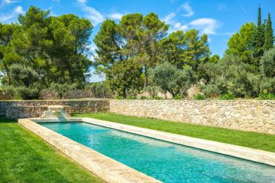 Salon avec canapé beige, fauteuils, table basse, télévision, cheminée en pierre et plafond avec poutres apparentes.