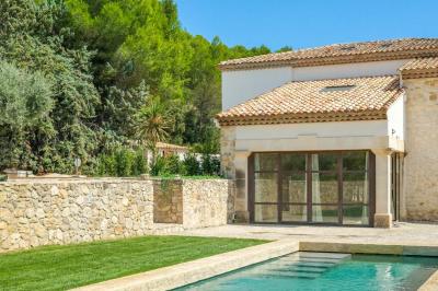 Salon avec canapé beige, fauteuils, table basse, télévision, cheminée en pierre et plafond avec poutres apparentes.