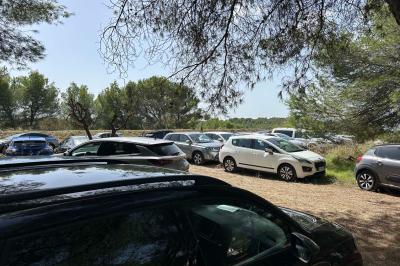 Salon avec canapé beige, fauteuils, table basse, télévision, cheminée en pierre et plafond avec poutres apparentes.