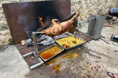 Salon avec canapé beige, fauteuils, table basse, télévision, cheminée en pierre et plafond avec poutres apparentes.