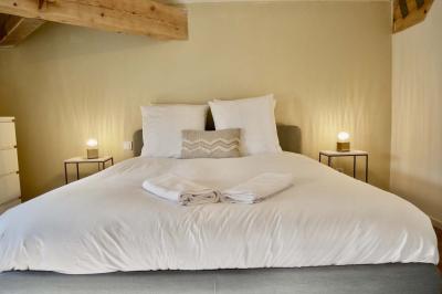 Salon avec canapé beige, fauteuils, table basse, télévision, cheminée en pierre et plafond avec poutres apparentes.