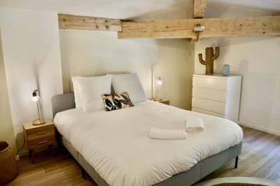 Salon avec canapé beige, fauteuils, table basse, télévision, cheminée en pierre et plafond avec poutres apparentes.