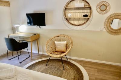 Salon avec canapé beige, fauteuils, table basse, télévision, cheminée en pierre et plafond avec poutres apparentes.