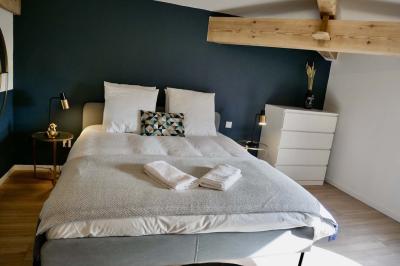 Salon avec canapé beige, fauteuils, table basse, télévision, cheminée en pierre et plafond avec poutres apparentes.