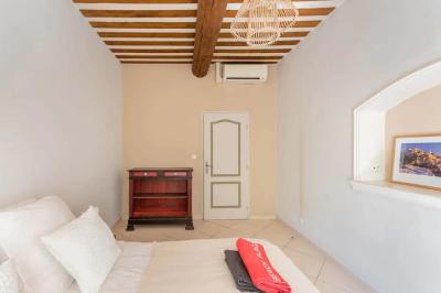 Salon avec canapé beige, fauteuils, table basse, télévision, cheminée en pierre et plafond avec poutres apparentes.