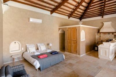 Salon avec canapé beige, fauteuils, table basse, télévision, cheminée en pierre et plafond avec poutres apparentes.