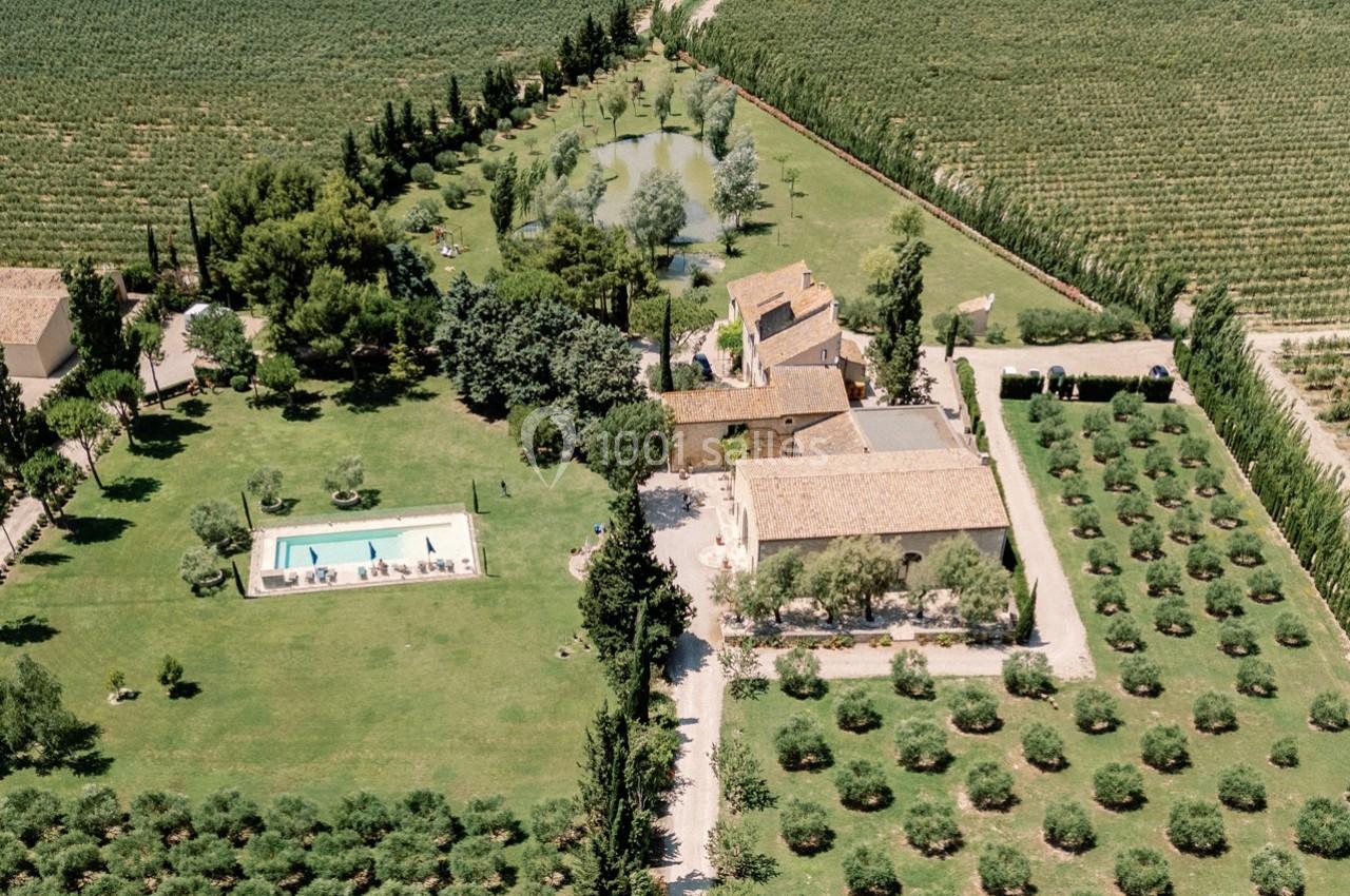 Vue aérienne d'une propriété rurale avec piscine, bâtiments en pierre, jardins et champs environnants.
