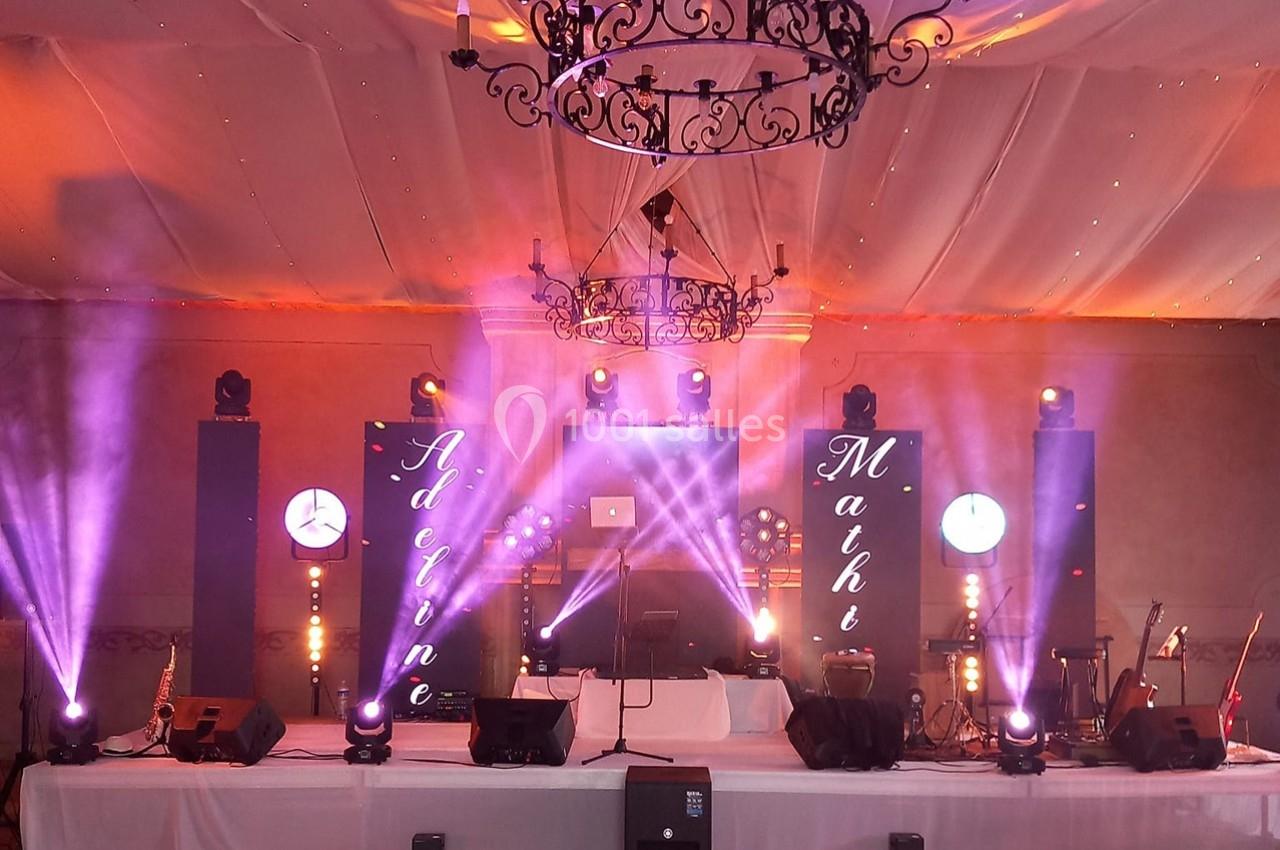 Scène décorée pour un événement avec éclairages colorés, écrans lumineux et instruments de musique.