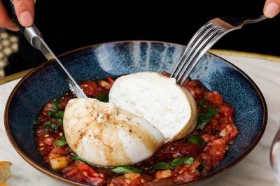 Deux verres de cocktails, l'un avec une tranche de citron, l'autre avec une tranche d'orange, tenus par deux mains.