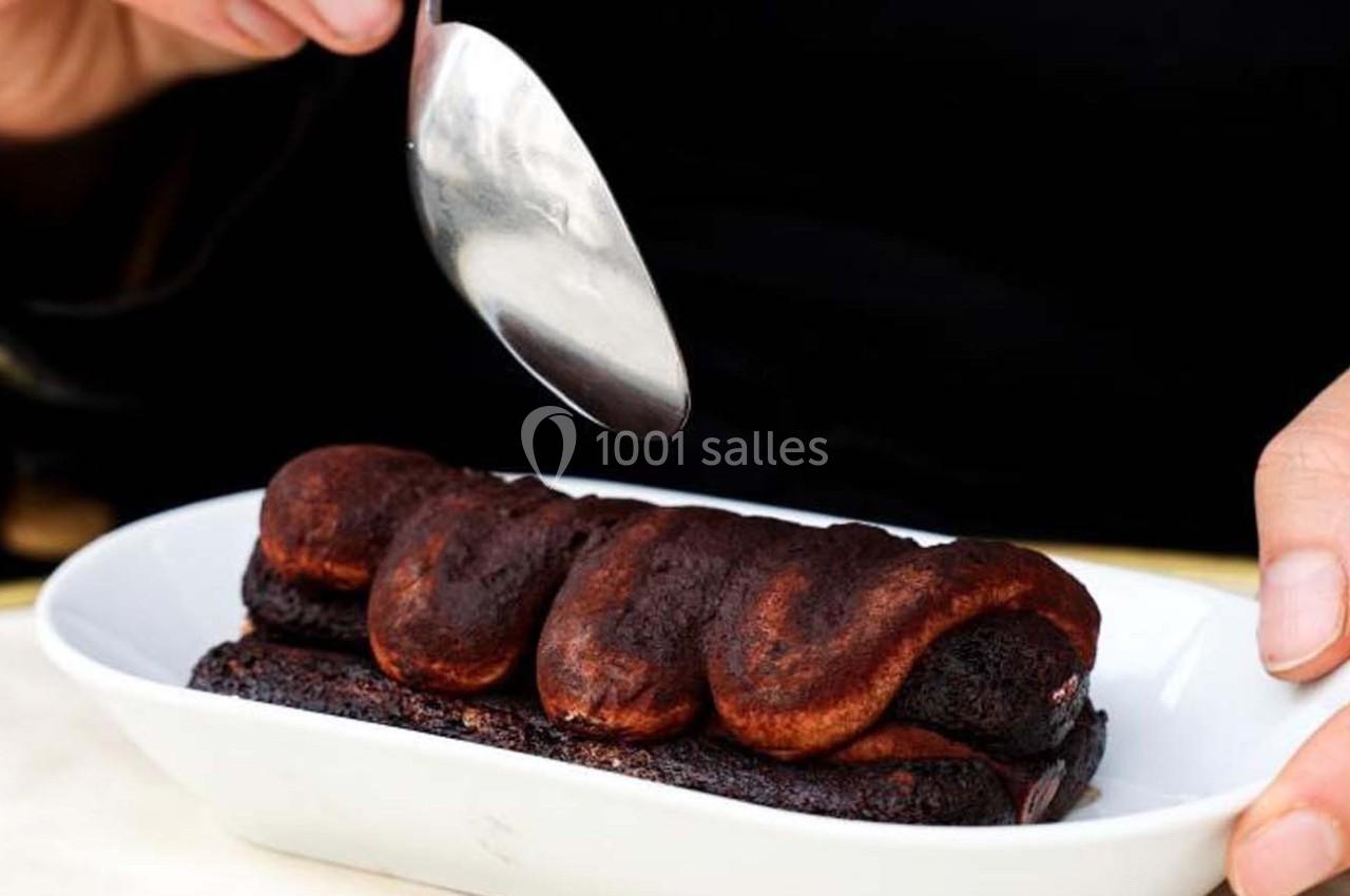 Une personne utilise une cuillère pour déguster un dessert au chocolat dans un plat blanc.