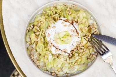 Deux verres de cocktails, l'un avec une tranche de citron, l'autre avec une tranche d'orange, tenus par deux mains.