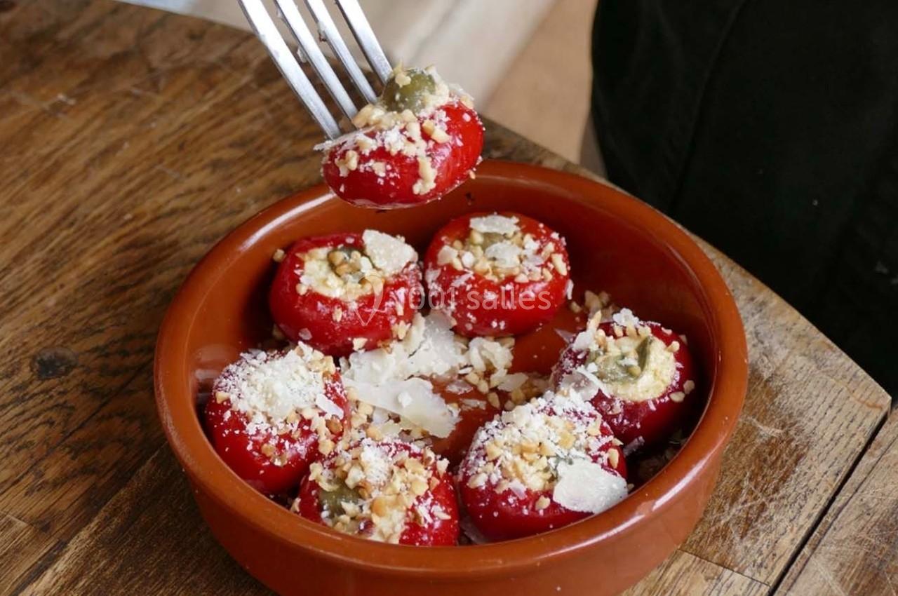 Tomates cerises farcies au fromage et aux noix dans un plat en terre cuite, une fourchette en saisit une.