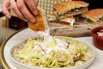 Deux verres de cocktails, l'un avec une tranche de citron, l'autre avec une tranche d'orange, tenus par deux mains.