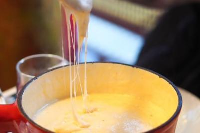 Deux verres de cocktails, l'un avec une tranche de citron, l'autre avec une tranche d'orange, tenus par deux mains.