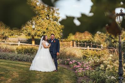 Étang entouré d'arbres et de buissons sous la neige, avec un lampadaire et des bancs dans un paysage hivernal.