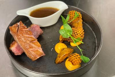 Un groupe de daims tachetés marche sur une pelouse verte devant une haie dense.