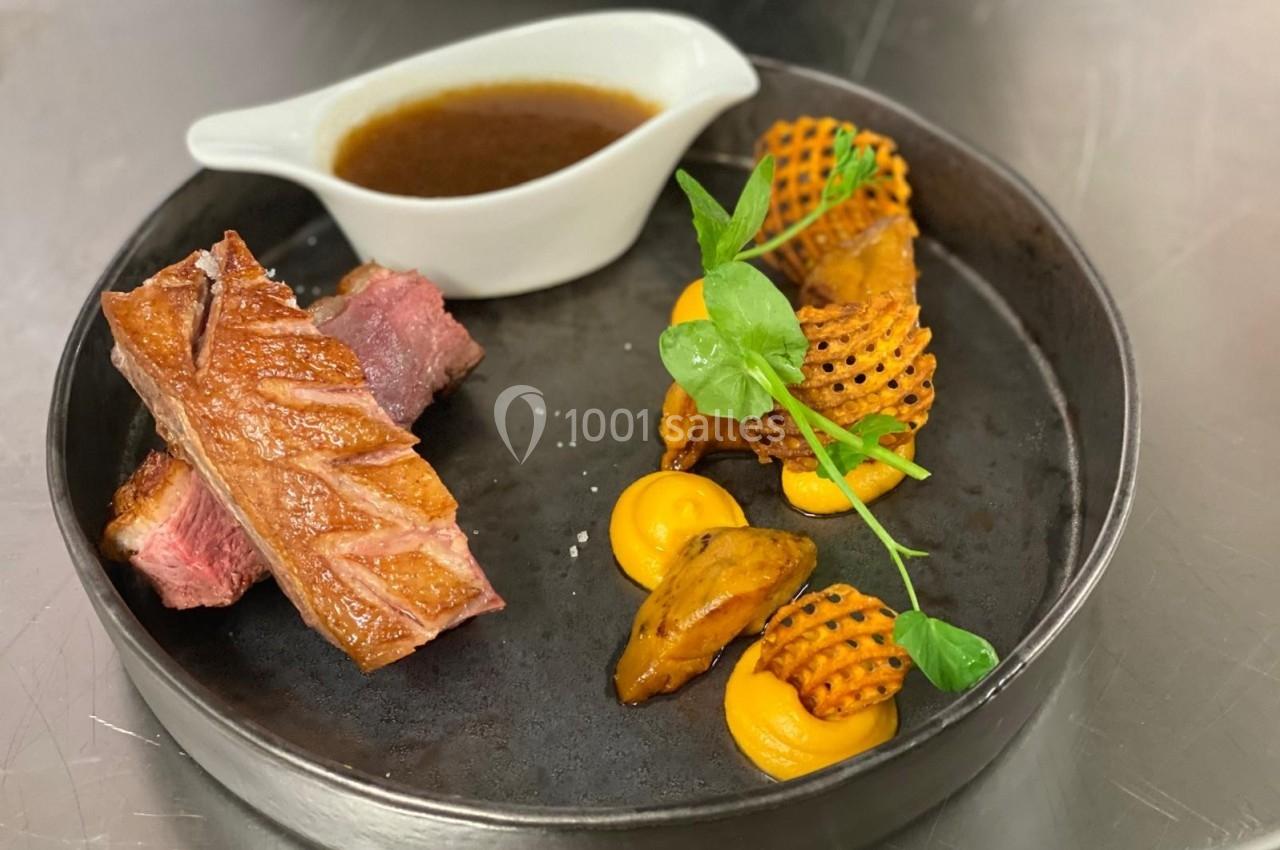 Assiette gastronomique avec viande grillée, purée de carottes, pommes gaufrettes, sauce brune et garniture verte.