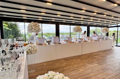 Salle de réception décorée avec des fleurs blanches, des tables élégantes et un éclairage rose tamisé.
