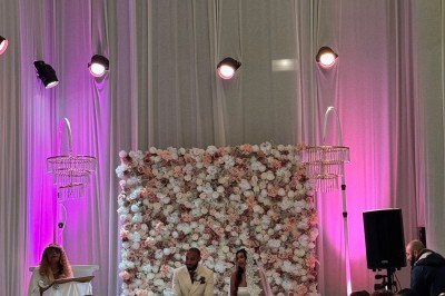 Salle de réception décorée avec des tables rondes, des chaises transparentes et des arrangements floraux blancs sous un…