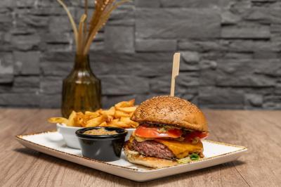 Entrée d'un café avec une grande terrasse, un parasol orange et des meubles en osier sous un ciel bleu.